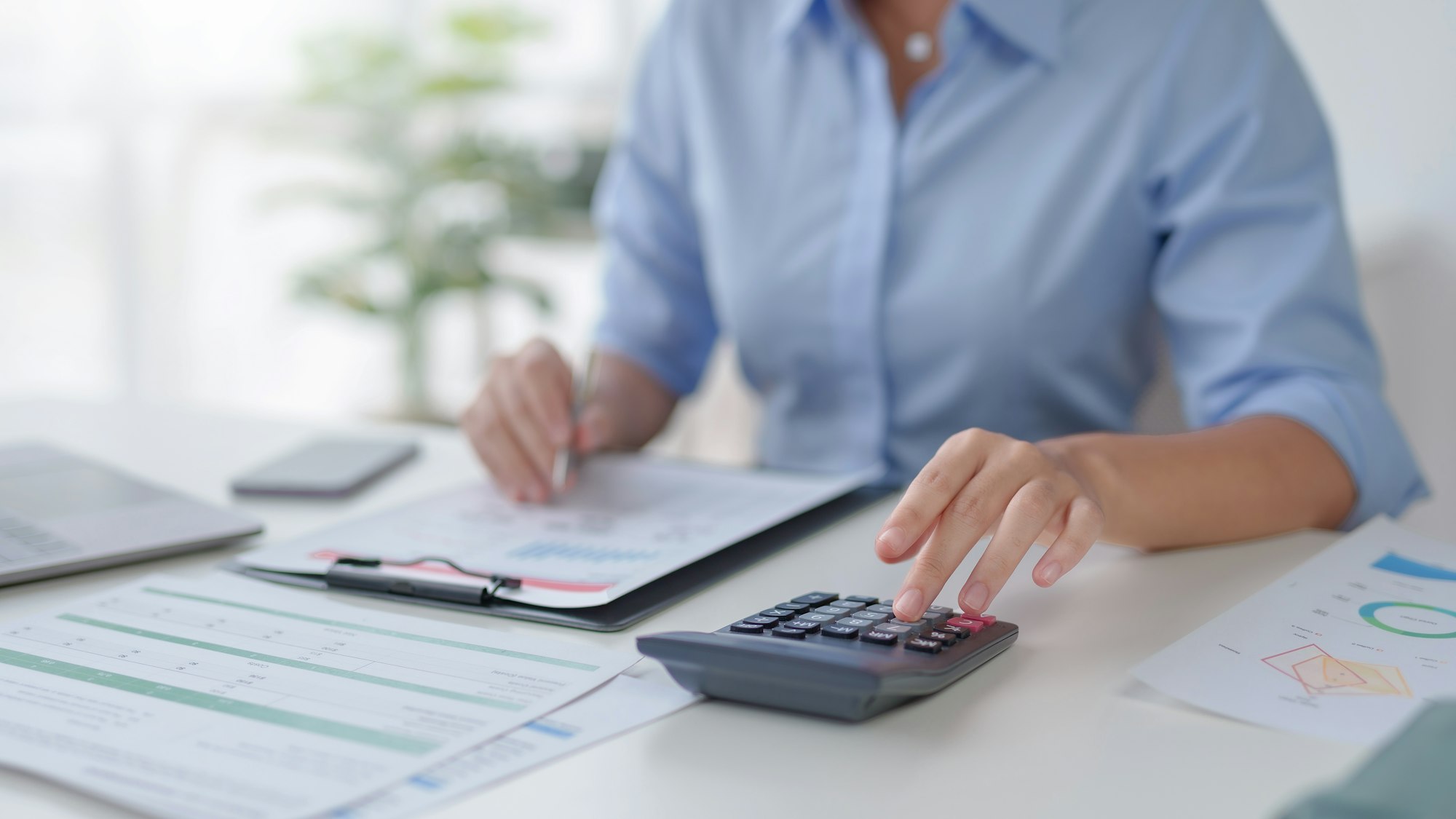 business woman hand using a calculator and take notes to check company finances